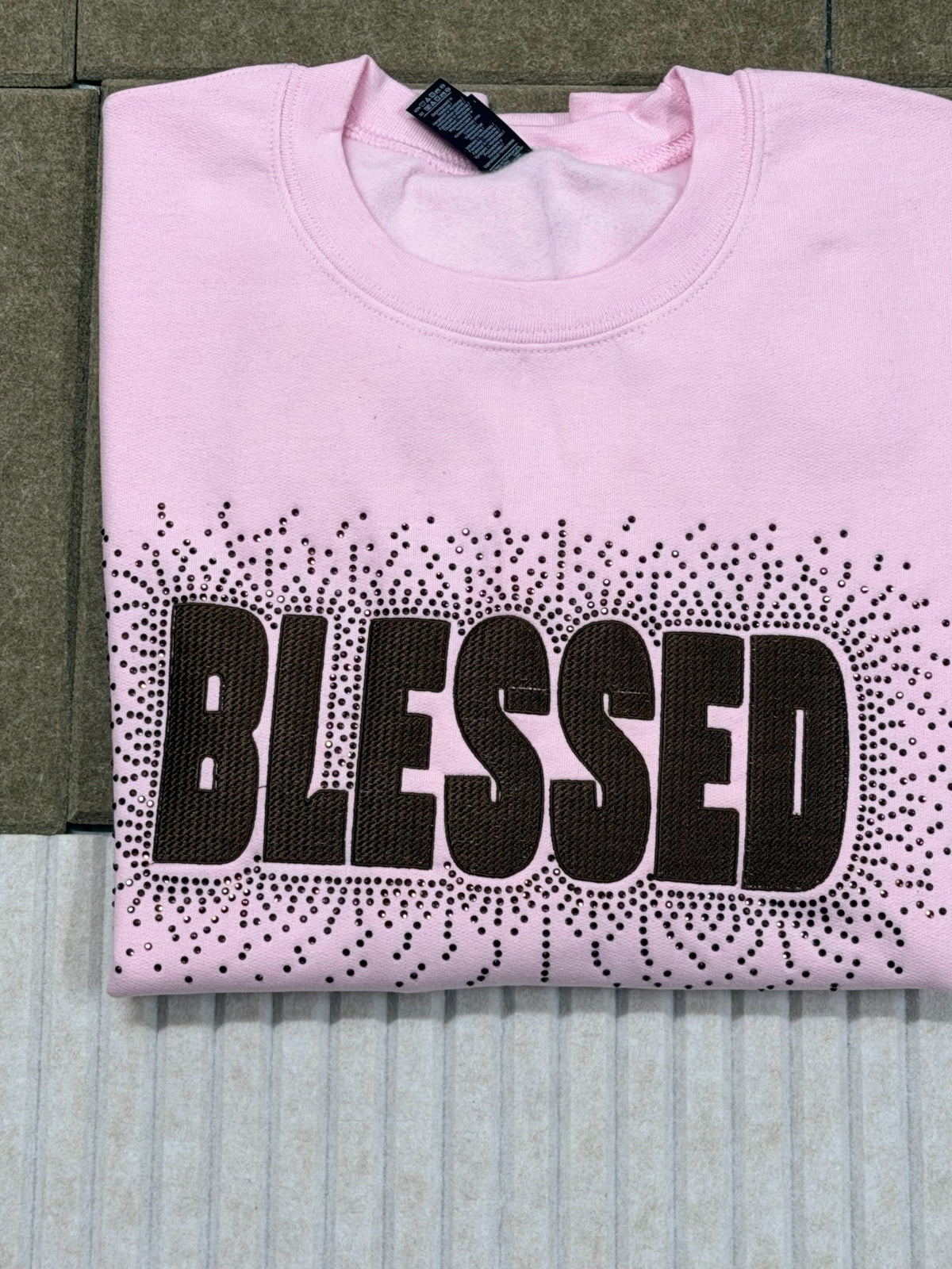 Folded pink Gildan Heavy Blend BLESSED embroidered rhinestone sweatshirt